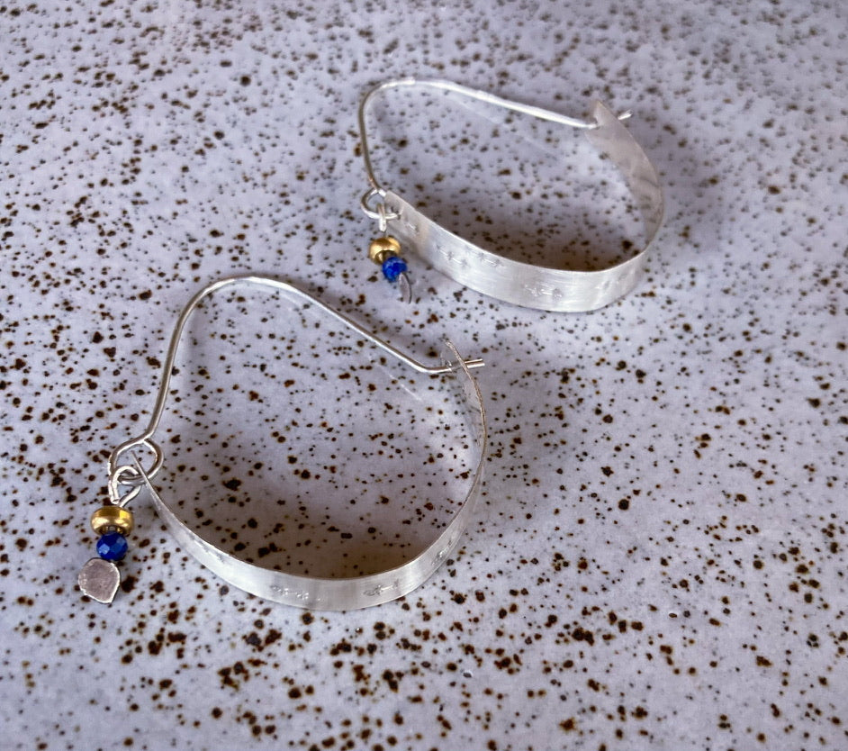 Swinging Sisters, textured sterling silver hoop earrings, featuring lapis lazuli and brass bead detail.