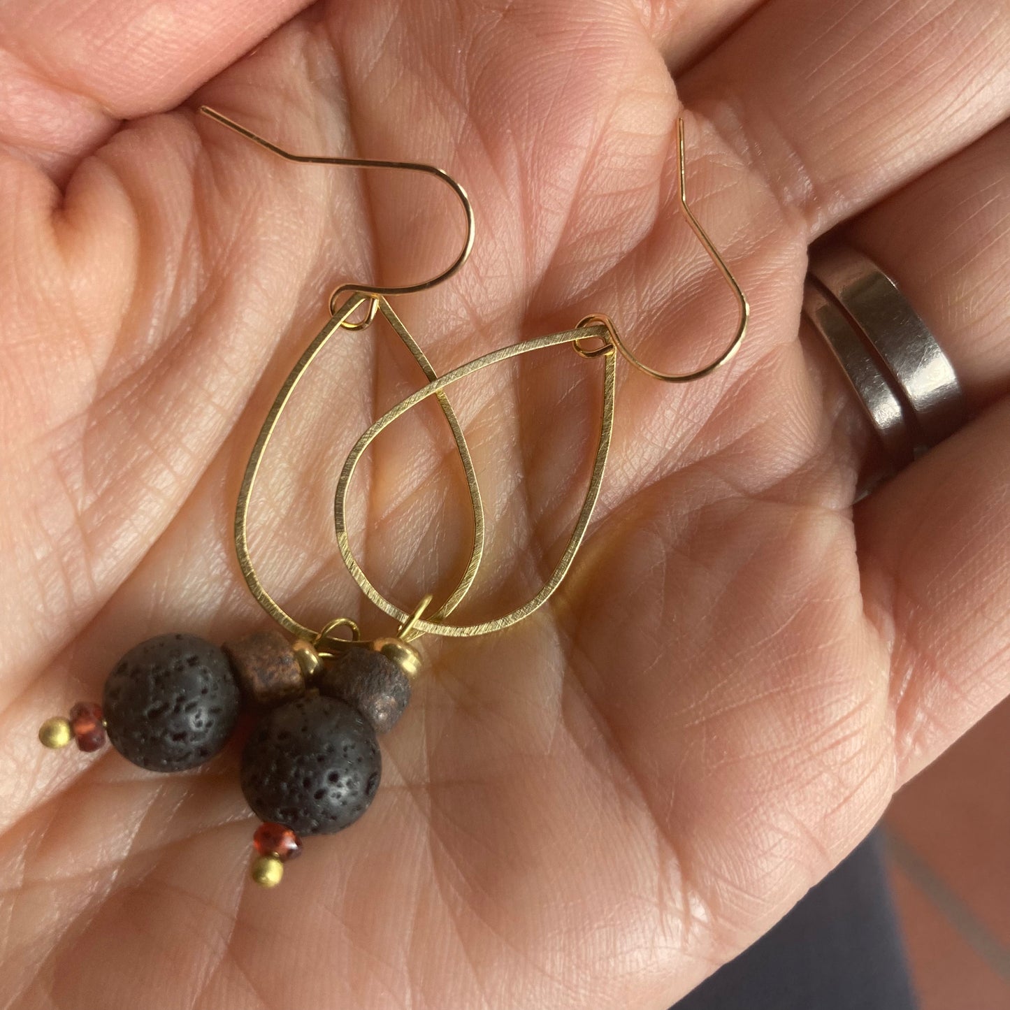 Yogis choice. Brass drop earrings, featuring lava stone and garnet bead, with gold plated hook.